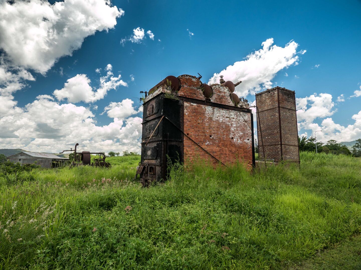 An old brick building sits in a green meadow