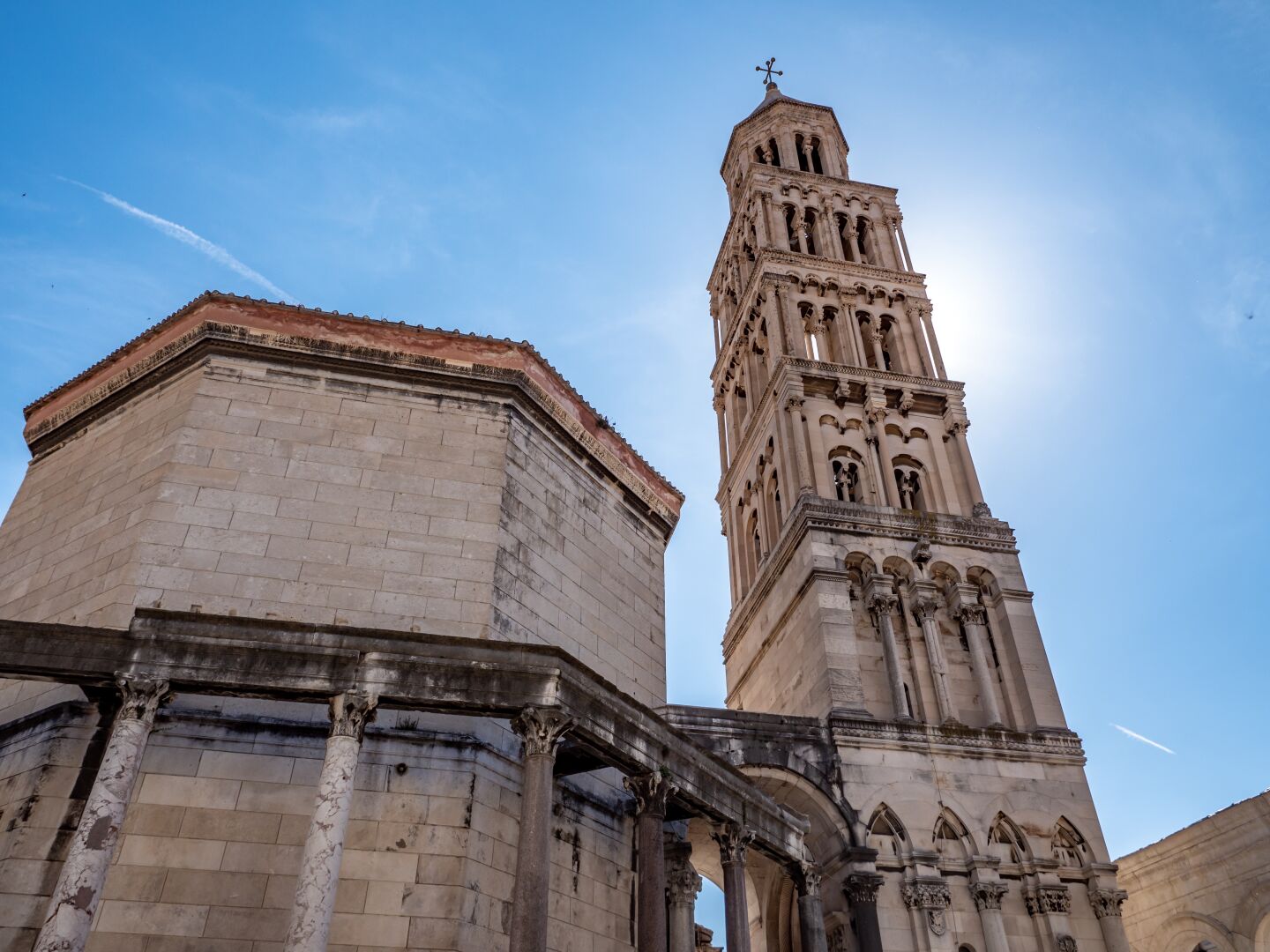 A large stone building and a stone tower with the blue sky behind them