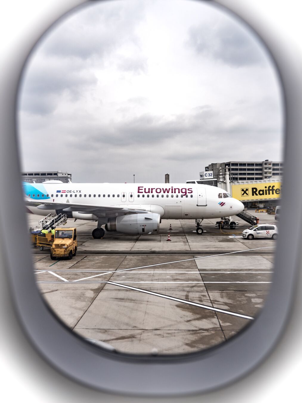 View out an airplane window looking at another Eurowings airplane at the airport gate