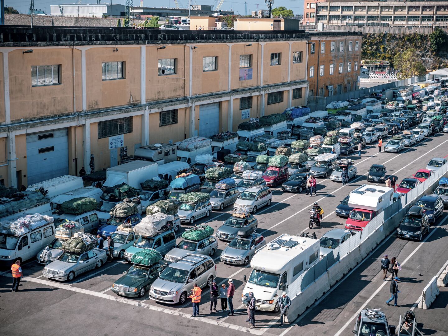 Cars packed with all kind of things on the roof wait in multiple lines to board the ferry