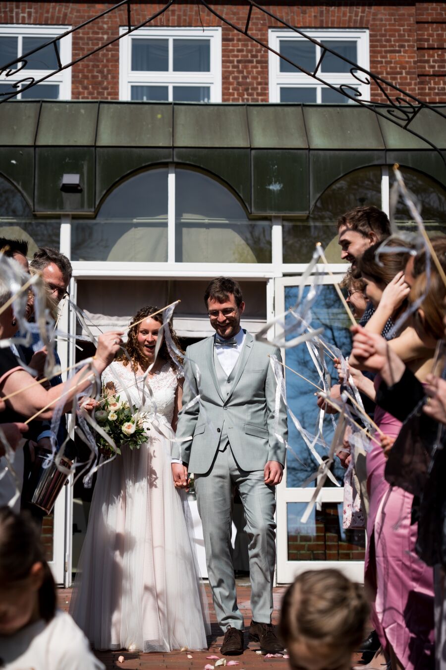 A couple walking out of a building into a the celebrating friends and family