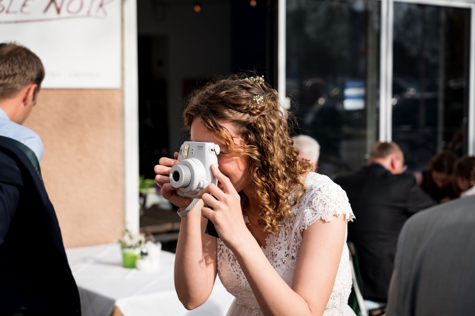 The bride takes a photo with a direct camera that prints the image right after taking it