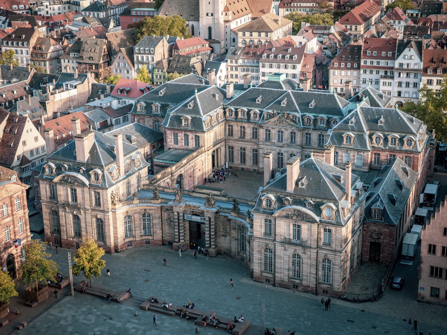An old stone building with blue windows and a blue roof photographed from a higher vantage point with the rest of the city around it