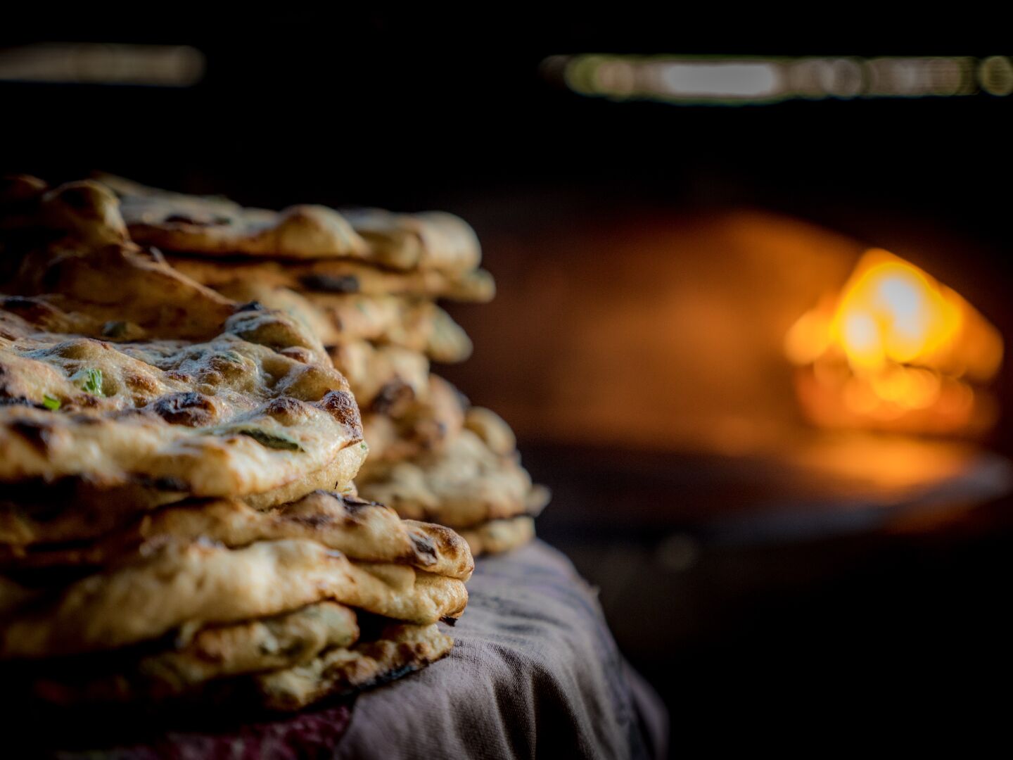 Flat bread with herbs on the left, with the oven visible in the background