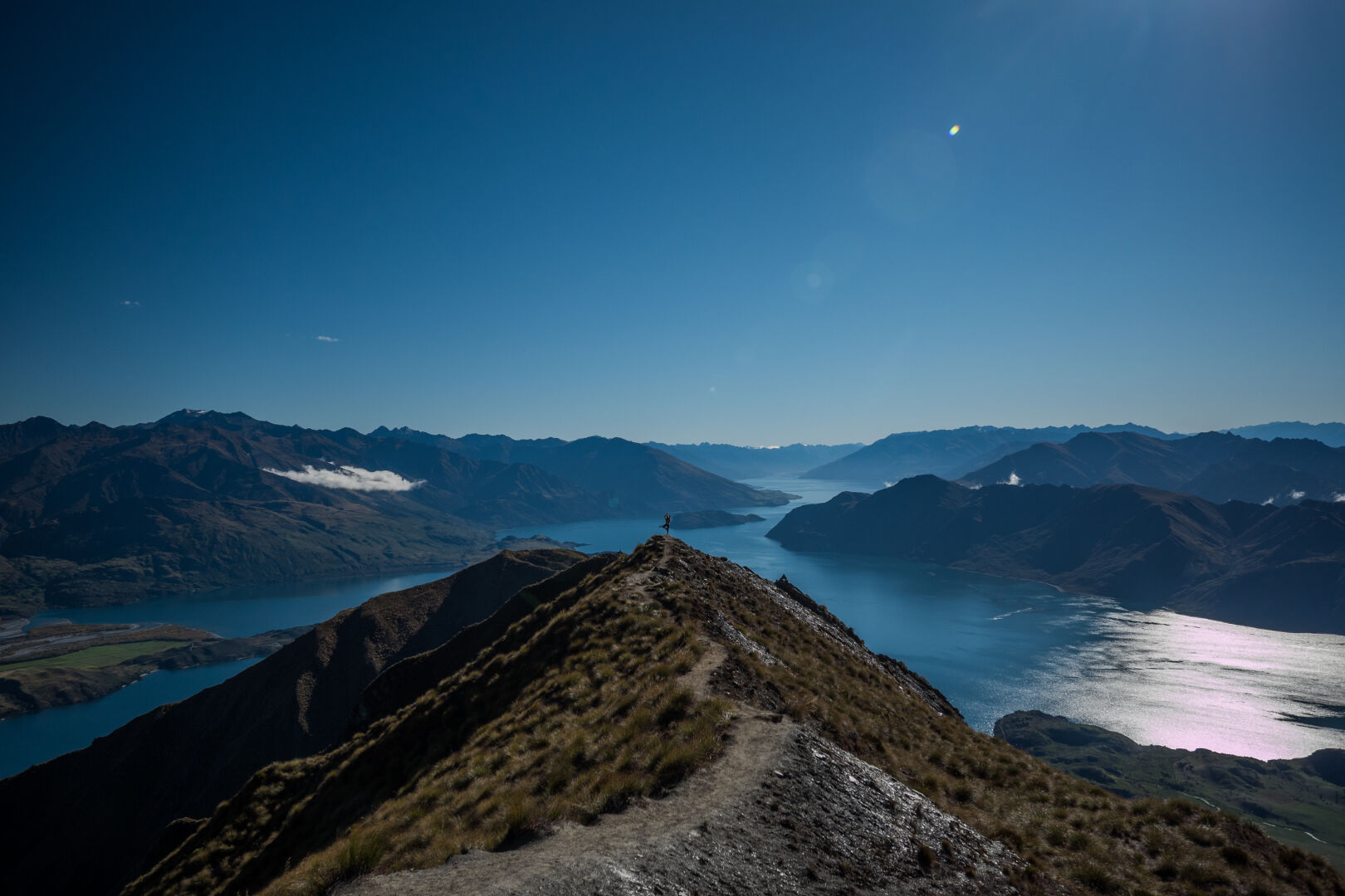 A mountain edge with a path on it leading towards the view across lakes