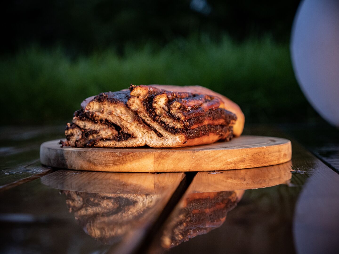 A cake on a wooden board on a wet floor mirroring the cake