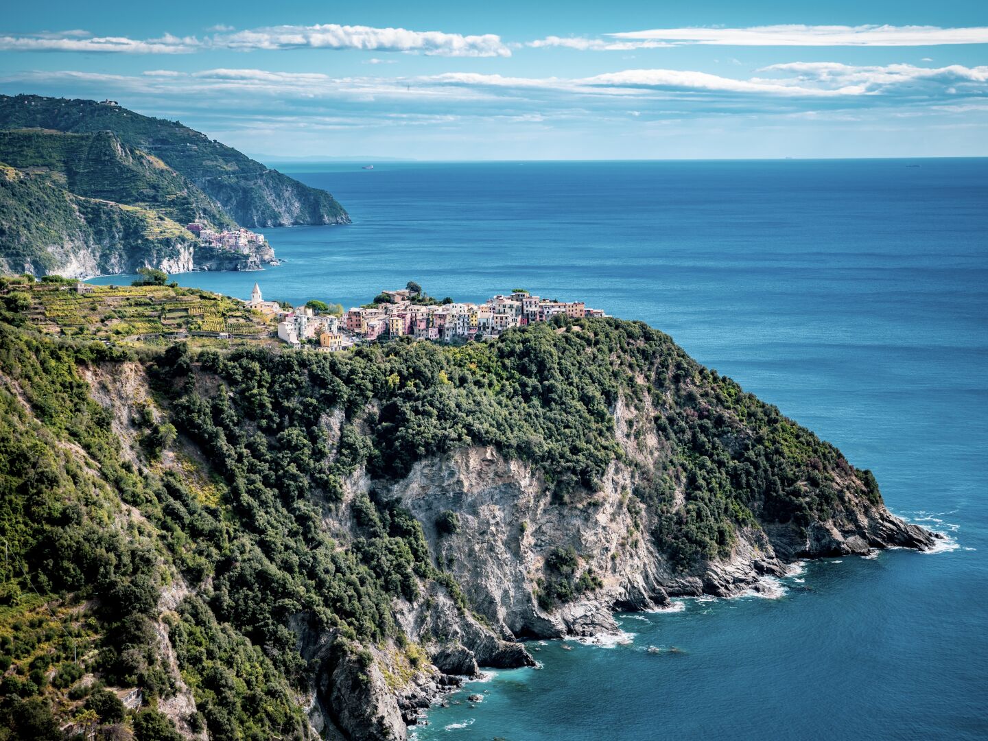 A small town sits on top of the coast with the sea on the right side, and the steep coats all around it